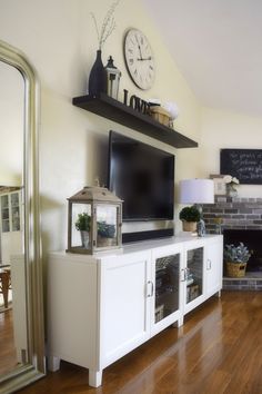 a flat screen tv sitting on top of a white entertainment center next to a fireplace