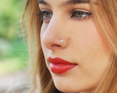 a woman with red lipstick and piercing on her nose