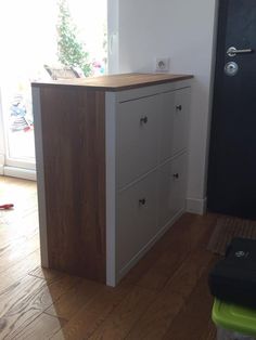 a white and brown dresser sitting on top of a hard wood floor next to a black door