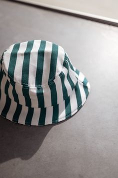 The hat is a stylish and comfortable accessory that is perfect for any casual outfit. Made from 100% cotton, it is breathable and soft to the touch. The green and white lines add a pop of color and a touch of personality, making it a unique and eye-catching piece. Matching set: Green Striped Denim Effect Kalina Shirt Green And White Striped Bucket Hat, Striped Cotton Casual Hat, Adjustable Striped Bucket Hat, Trendy Green Wide Brim Sun Hat, Striped Bucket Hat For Spring Beach Days, Striped Bucket Hat For Beach In Spring, Striped Bucket Hat For Spring Beach Outings, Trendy Green Sun Hat With Curved Brim, White Cotton Vacation Hat