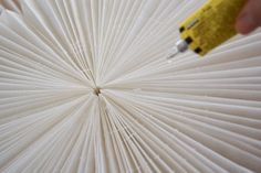 a close up of a person holding a pen and writing on an open book that is folded in paper