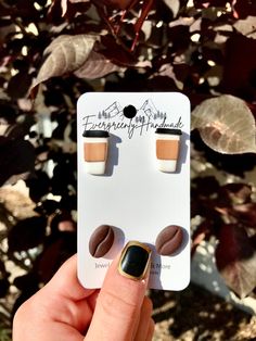 someone is holding up a pair of coffee earrings