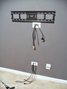 the tv is hanging on the wall and wires are plugged in