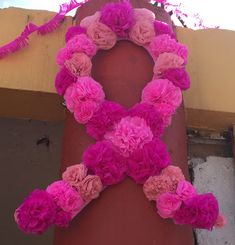 pink flowers are arranged in the shape of an x on a red pole near a yellow building