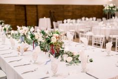 the tables are set with white linens and floral centerpieces