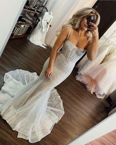 a woman taking a selfie in front of a mirror wearing a white dress with sequins