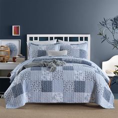 a bed with blue and white bedspread in a bedroom next to a plant