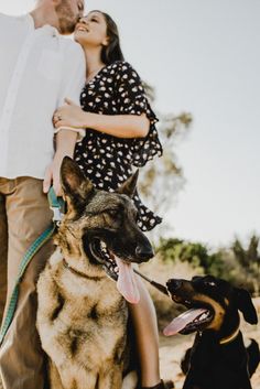 a man and woman standing next to two dogs