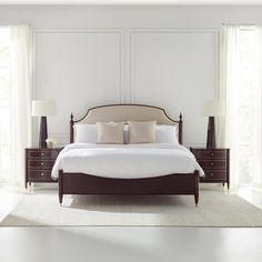 a bed with white sheets and pillows in a bedroom next to two lamps on either side of the bed