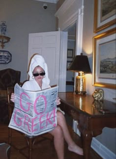 a woman sitting in a chair with a towel on her head and reading a newspaper