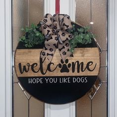 a welcome sign hanging on the front door with a dog's paw print bow