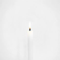 a single white candle with a black dot in the middle on a plain background that appears to be empty