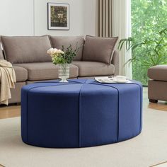 a living room filled with furniture and a blue ottoman sitting on top of a rug