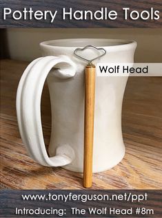 a white pottery mug with a wooden handle