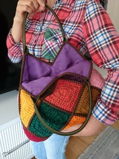 a woman holding a multicolored purse in her hands