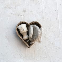 a heart - shaped basket with two toothbrushes in it on a white wall