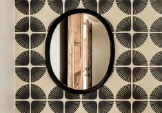 a round mirror on the wall in front of a black and white pattern