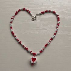 a red and white beaded necklace with a heart shaped pendant on the end of it