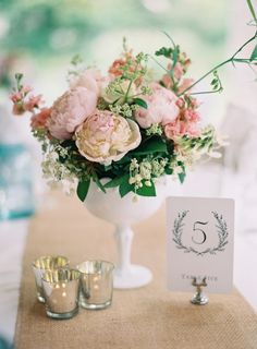 a vase filled with flowers sitting on top of a table next to two silver cups