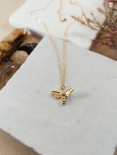 Elegant and timeless, our Bee Charm Gold Necklace features a delicate bee pendant crafted in beautiful 18K gold. Perfect for adding a touch of nature-inspired beauty to any outfit, this necklace is both sophisticated and versatile, making it an ideal gift or a cherished addition to your jewelry collection. Features & Benefits: 🐝 One-of-a-Kind Creations Each piece of Bee Love Handmade Jewelry is a labor of love, meticulously handcrafted to reflect the intricate beauty of honeycombs and the tireless dedication of bees. No two pieces are alike, ensuring your jewelry is as unique as you are. 🌱 Ethically Handmade Bee Love Handmade Jewelry is more than just an accessory; it's a statement of your values. Thoughtfully crafted with sustainability at its core, every piece is a testament to ethical Tiny Gold Necklace For Her, Handmade Honey Color Jewelry Gift, Handmade Honey Jewelry For Gift, Handmade Honey-colored Jewelry For Gifts, Bee Jewelry, Bee Pendant, Jewelry Minimalist, Bee Necklace, Bee Charms