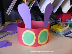 a pink paper cup with scissors in it on a desk next to books and magazines