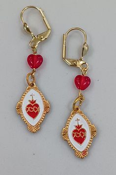 Sacred heart of Jesus earrings feature Czech pressed glass hearts and enameled medals with a prayer on the reverse. Enamel Earrings With Heart Charm As Gift, Enamel Heart Charm Earrings As Gift, Valentine's Day Enamel Jewelry Nickel-free, Valentine's Day Nickel-free Enamel Jewelry, Heart-shaped Miraculous Medal Jewelry Gift, Heart Shaped Miraculous Medal Jewelry Gift, Jesus Earrings, Glass Hearts, Sacred Heart Of Jesus