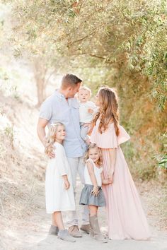 the family is posing for a photo together in front of some trees and dirt road