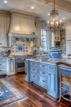 a blue and white kitchen with an island, chandelier, sink, stove and refrigerator