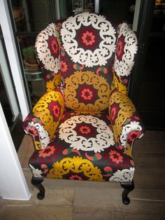 a colorful chair sitting on top of a wooden floor next to a doorway with an open door