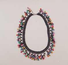 a multicolored beaded necklace on a white surface with an empty space in the middle