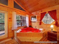 a hot tub in the corner of a room with red drapes on the windows