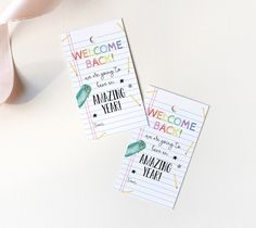 two personalized welcome tags on top of a white surface with a pink ribbon next to it