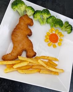 a white plate topped with fries and broccoli next to a piece of fried chicken