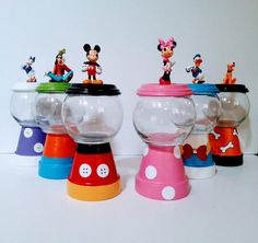 there are many different toy items in the glass bowl on the table, including mickey mouse and other toys