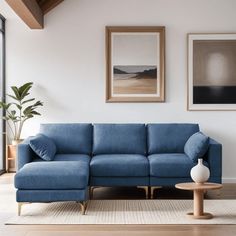 a living room with a blue couch and two pictures on the wall above it, along with a coffee table