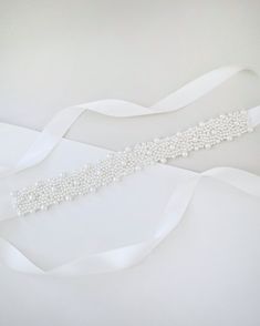 "A statement sash is encrusted with beautiful pearls attached on bridal white double-faced satin ribbon. This classic pearly belts creates a romantic finishing touch to your bridal gown, bridesmaids and flower girls, or as hair accessories.  DETAIL: Adult Size 108\" Kids Size 78\" Headband Size 60\" Applique size: 12\" length, 2\" wide/1.25\" wide - We DO NOT offer refunds.  Selected items are eligible for EXCHANGE ONLY within 14 days of delivery date.   All accessories are FINAL SALE. - We are Elegant Satin Bridal Accessories For Wedding, Elegant Bridal Belt With Satin Bow For Bridesmaid, Elegant Bridal Belt With Satin Bow For Wedding, Wedding Bridal Belt With Sashes In Satin, Satin Bridal Belt With Ribbon For Wedding, Elegant White Bridal Belt With Satin Bow, White Satin Bridal Belt With Sashes, Elegant Bridal Accessories With Pearl Embroidery, Elegant Pearl Embroidered Bridal Accessories