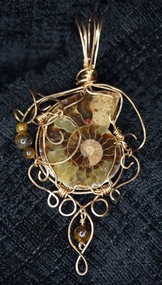 This pendant is a hand made bronze wire wrapped ammonite, accented with tiger eye beads.  This will be shipped with an eighteen inch length of satine cord, so that the length of the necklace can be adjusted.  Alternatively, a bronze chain can be fabricated for an additional charge.  You can see me make items like this live on my Twitch.tv channel at https://www.twitch.tv/growlingmousestudio Spiral Wire Wrapped Brass Jewelry, Spiral Brass Wire Wrapped Jewelry, Nature-inspired Gold Wire Wrapped Jewelry, Bronze Spiral Wire Wrapped Jewelry, Bronze Wire Wrapped Spiral Jewelry, Spiral Copper Necklace In Gold Color, Unique Brown Spiral Jewelry, Brown Spiral Jewelry As A Gift, Gold Spiral Necklace In Copper