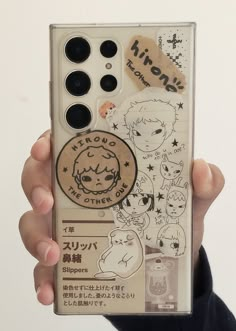 a person holding up a cell phone case with some stickers on it's side