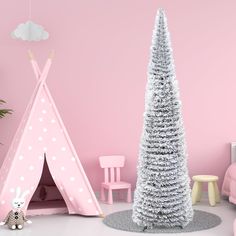 a white christmas tree sitting next to a pink teepeet in a child's room