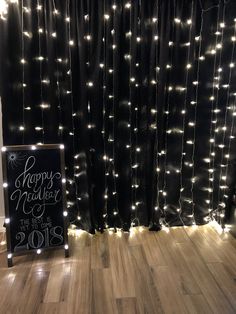 a happy new year's eve sign in front of a black curtain with lights