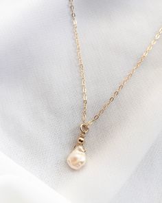 Classic and minimalist, a beautiful freshwater Keshi pearl hangs from our signature thin cable chain. With its organic shape and gorgeous luster, no two pearls are the same. Color ranges from cream and off-white to champagne. This dainty single pearl necklace is handcrafted in Gold Filled or Sterling Silver. Wear alone or layer with your favorite everyday necklaces. Our model is wearing the 16" length necklace. Features: Single Freshwater Keshi Pearl (Approximately 7mm to 10mm In Size) Delicate Pearl Minimalist Necklace, Perl Neckles Simple, Formal Jewellery, Minimal Choker, Everyday Necklaces, Boho Queen, Gold Drop Necklace, Simple Pearl Necklace, Keshi Pearl Necklace