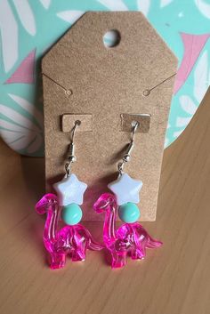 Dangle dinosaur earrings made with plastic beads 🦕 Hypoallergenic! Playful Plastic Dangle Jewelry, Playful Beaded Earrings For Gift, Playful Pink Beaded Earrings, Pink Hypoallergenic Plastic Earrings, Playful Resin Dangle Earrings, Playful Pink Plastic Earrings, Handmade Pink Plastic Earrings, Handmade Plastic Dangle Earrings, Goofy Earrings