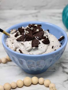 a blue bowl filled with ice cream and oreo chips on top of a marble counter