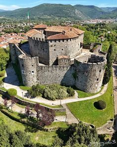 an aerial view of a castle with trees and mountains in the background