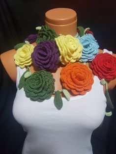 a woman wearing a white tank top with multicolored crocheted roses on it