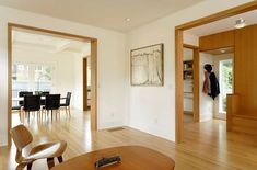 an open living room and dining area with hardwood floors, white walls and wood furniture