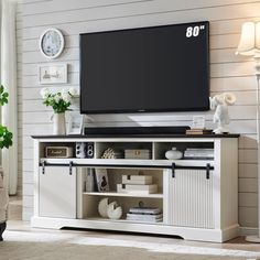 an entertainment center with a flat screen tv mounted on it's sideboard in a living room