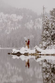 two people standing on the edge of a lake covered in snow