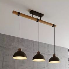 three lights are hanging from the ceiling in a room with concrete walls and flooring