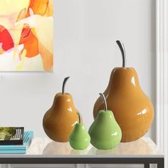 three pears on a table in front of a painting